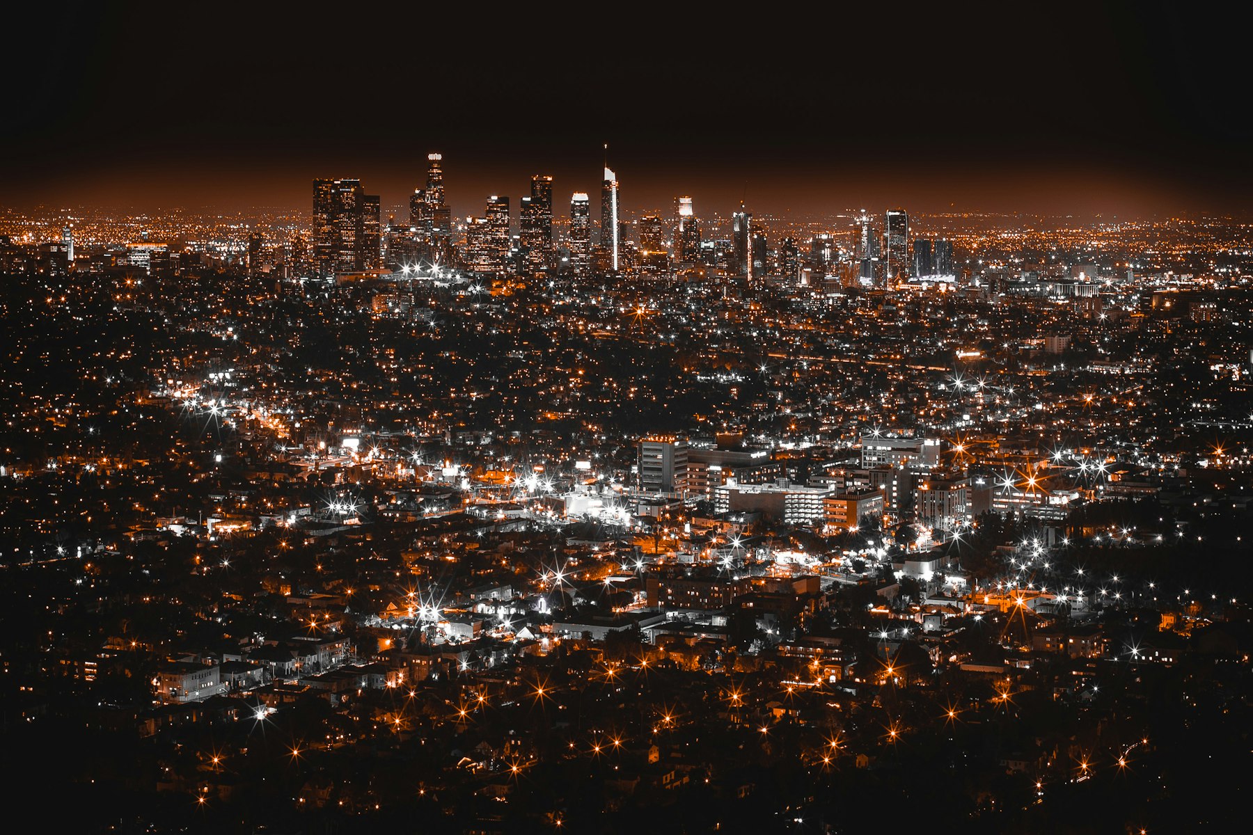 A city at night seen from above, thousands of lights spread across the dark