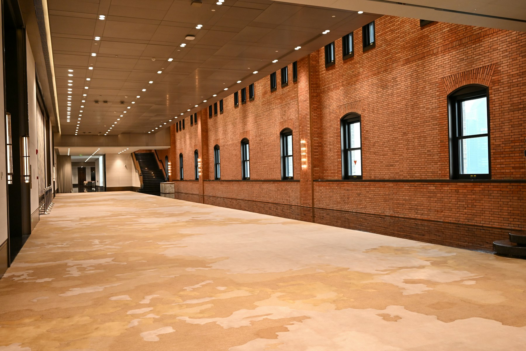 A long, empty hall with brick walls and soft overhead lights