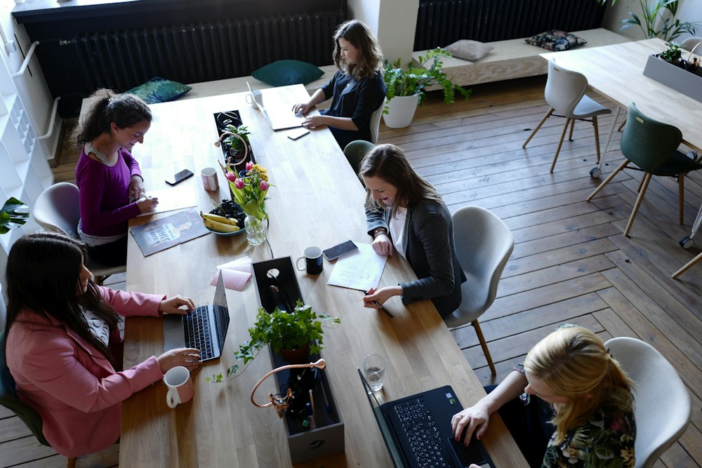 A team working together around a wooden table with laptops